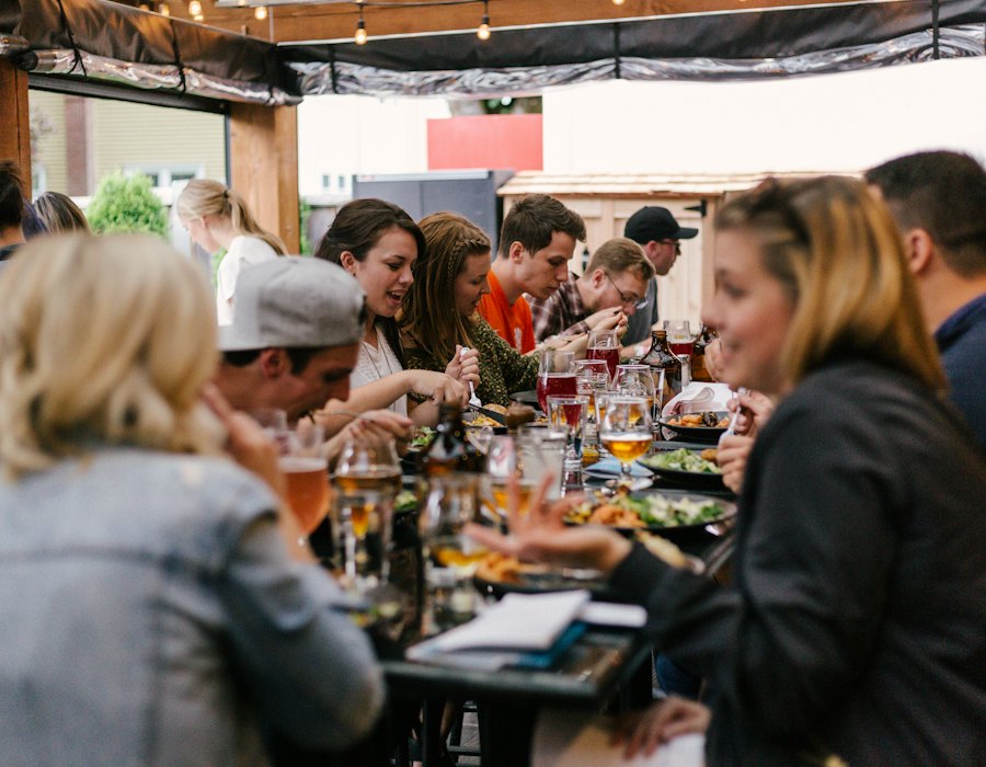 Lange gedeckte Tafel, viele Menschen essen und reden